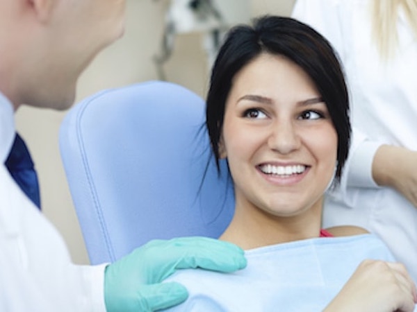 Dentist explaining a service to a female patient in a dental chair
